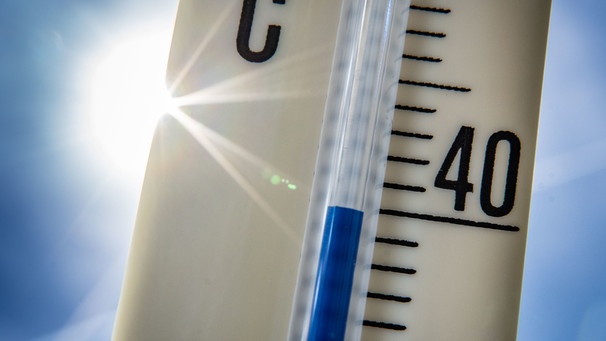 Ein Außenthermometer zeigt vor dem blauen Himmel und der Sonne eine Temperatur von nahezu 40 Grad Celsius an. | Bild: dpa-Bildfunk/Frank Rumpenhorst