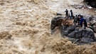 Mehr Katastrophen durch Klimawandel und Extremwetter: Nepalesen stehen auf einem Felsen am Ufer des überfluteten Flusses Bagmati und fotografieren die Strömung (Archivbild 2020) | Bild: Niranjan Shrestha/AP/dpa