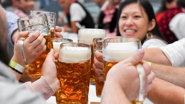 21.09.2019, Bayern, München: Auftakt zum Oktoberfest. Besucher prosten sich mit Bierkrügen zu. Das größte Volksfest der Welt dauert bis zum 6. Oktober. Foto: Tobias Hase/dpa +++ dpa-Bildfunk +++ | Bild: dpa-Bildfunk/Tobias Hase