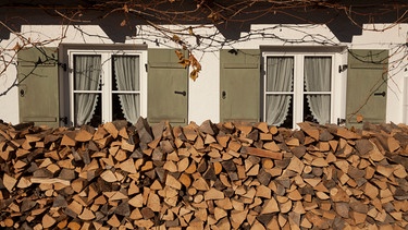 Holzlege vor einem Haus mit zwei Fenstern | Bild: BR/Herbert Ebner