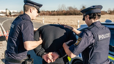 Eine Polizistin und ein Polizist verhaften einen jungen Mann und legen ihm Handschellen an. | Bild: BR/Fabian Stoffers