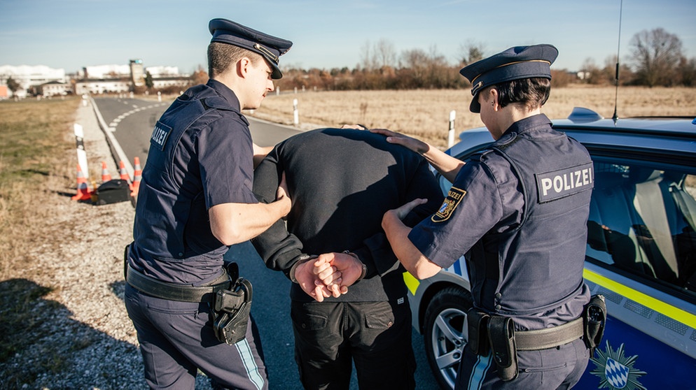 Eine Polizistin und ein Polizist verhaften einen jungen Mann und legen ihm Handschellen an. | Bild: BR/Fabian Stoffers