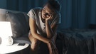 Eine erschöpfte Frau, die an Schlaflosigkeit leidet, sitzt auf einem Bett und denkt nach. | Bild: stock.adobe.com/stokkete
