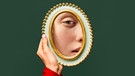 Eine Frau betrachtet ihr Spiegelbild in einem kleinen ovalen Spiegel. | Bild: stock.adobe.com/Lustre