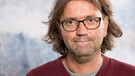 Andreas Putzer ist Archäologe, hat einen roten Pullover an und schaut in die Kamera.  | Bild: privat