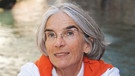 Donna Leon lächelt in die Kamera. Auf ihren Schultern liegt ein orangefarbender Pulli.  | Bild: Regine Mosimann 