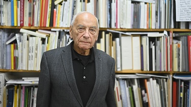 Eugen Gomringer steht vor einem Bücherregal.  | Bild: picture alliance / Nicolas Armer