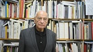 Eugen Gomringer steht vor einem Bücherregal.  | Bild: picture alliance / Nicolas Armer