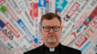 Hans Zollner mit Brille. Er steht vor einem farbigen Hintergrund und schaut in die Kamera. | Bild: AP Photo/Andrew Medichini