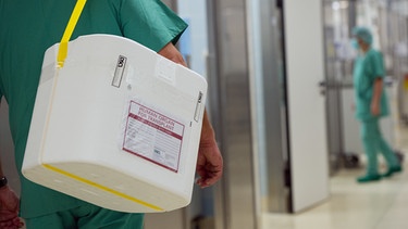 Ein Mitarbeiter eines Krankehauses trägt eine Kühlbox mit einem Spenderorgan durch den Flur des Krankenhauses | Bild: dpa-Bildfunk_Soeren Stache