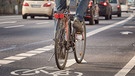Ein Fahrradfahrer fährt im Straßenverkehr auf einer Fahrradspur (Symbolbild) | Bild: stock.adobe.com/Kara