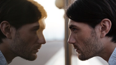 Ein Mann betrachtet sein Spiegelbild im Fenster. | Bild: Colourbox.com/ Dean Drobot