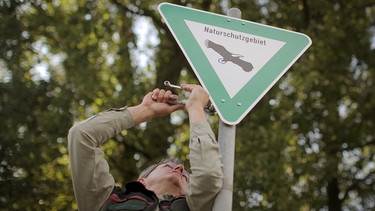 Ein Förster montiert ein neues Naturschutzgebiet-Schild. | Bild: picture-alliance/dpa