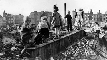 Eine Gruppe Kinder spielt in den Trümmern einer zerstörten Stadt im Deutschland der Nachkriegszeit. (Undatiertes Archivbild aus den 1940er Jahren) | Bild: picture alliance / dpa