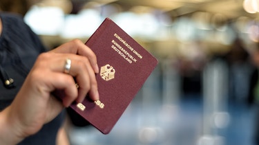 Eine Frau hält einen deutschen Reisepass in der Hand. | Bild: stock.adobe.com/cameris
