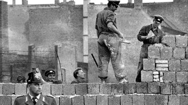 Die Berliner Mauer wird gebaut, im Vordergrund ein Polizist aus dem Westen - 1961 | Bild: picture-alliance/dpa