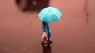 Eine Frau schützt sich vor dem Monsun-Regen in Mumbai, Indien | Bild: picture-alliance/dpa