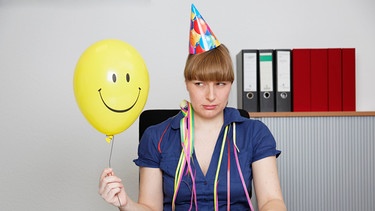 Eine Frau hält einen Luftballon mit einem Lachsmiley | Bild: picture alliance / Westend61 | Westend61 / Anja Bäcker