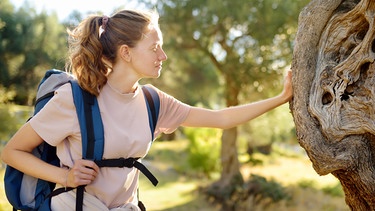 Frau mit Rucksack berührt Baum  | Bild: colourbox.com