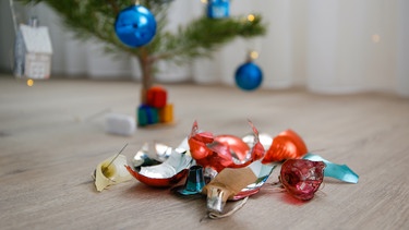 Zerbrochene Kugeln vor einem Weihnachtsbaum | Bild: colourbox.com