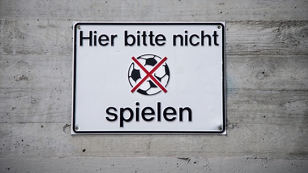 Ein Schild mit der Aufschrift "Hier bitte nicht spielen" und einem durchgestrichenen Fußball hängt am 22.08.2013 in Nürnberg an der Betonfassade eines Wohnhauses. | Bild: David Ebener/dpa