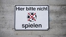 Ein Schild mit der Aufschrift "Hier bitte nicht spielen" und einem durchgestrichenen Fußball hängt am 22.08.2013 in Nürnberg an der Betonfassade eines Wohnhauses. | Bild: David Ebener/dpa