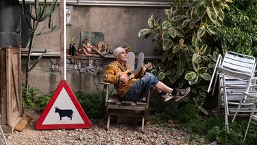 Manu Chao sitzt mit Ukulele schief in einem Stuhl | Bild: Moises Samam Magnum