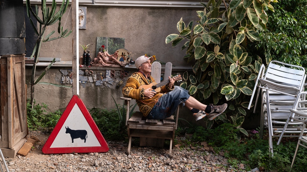 Manu Chao sitzt mit Ukulele schief in einem Stuhl | Bild: Moises Samam Magnum