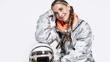 Eine Frau sitzt im Astronautenanzug auf dem Boden | Bild: Randall Slavin