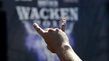 Ein Festivalbesucher zeigt auf dem Festivalgelände in Wacken (Schleswig-Holstein) das Zeichen der Heavy-Metal-Fans, die "Pommesgabel" | Bild: picture alliance / dpa | Carsten Rehder