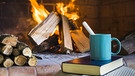 Buch mit Tasse vor einem Kaminfeuer | Bild: colourbox.com