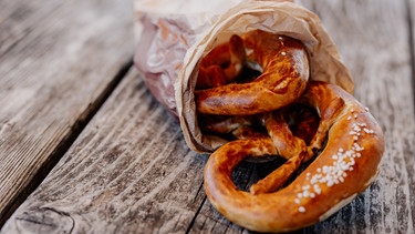 Brezen in einer Bäckertüte auf einem Holztisch. | Bild: BR/Marina Giglinger