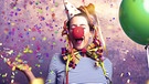 Eine Frau im Clownskostüm mit Konfetti und Luftschlangen. | Bild: stock.adobe.com/drubig-photo