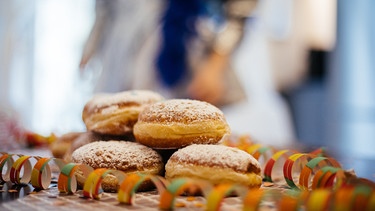 Krapfen stehen bei einer Faschingsparty auf dem Tisch. | Bild: BR/Fabian Stoffers