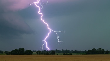 Ein Blitz leuchtet über einer Landschaft auf.  | Bild: dpa-Bildfunk/Patrick Pleul