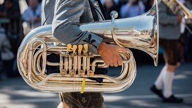 Ein Mann in Tracht trägt eine Tuba | Bild: BR/Max Hofstetter