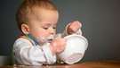 Ein Kleinkind kleckert beim Essen von Joghurt | Bild: picture alliance / Caro | Teich