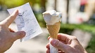 Ein Mann hält eine Waffel mit einer Kugel Eis im Sommer zusammen mit einem Kassenbon. (Symbolbild) | Bild: picture alliance / CHROMORANGE | Michael Bihlmayer