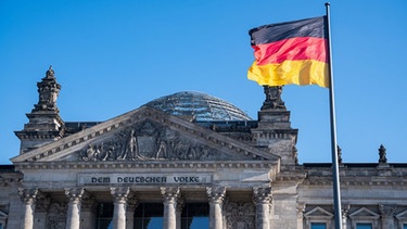 Eine Deutschlandfahne weht vor dem Reichstagsgebäude in Berlin | Bild: picture alliance / SZ Photo | Olaf Schülk