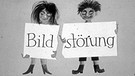 Mann und Frau halten zerrissenes Plakat "Bild-Störung" in den Händen. | Bild: BR / Historisches Archiv