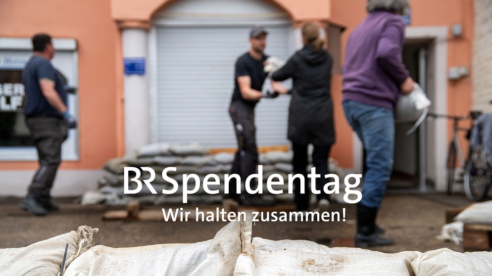 Anwohner am Ufer der Donau in Regensburg schichten Sandsäcke. Schrift: BR Spendentag  Wir halten zusammen! | Bild: picture alliance/dpa | Pia Bayer